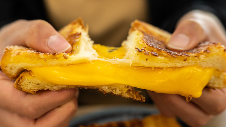 hands pulling apart grilled cheese sandwich