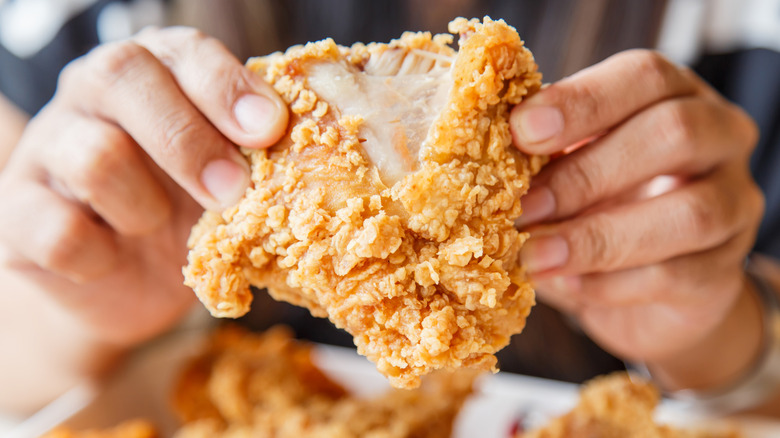 Pulling apart a piece of crispy fried chicken