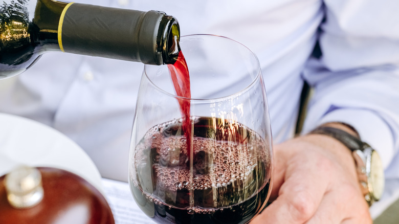 A man pouring red wine into a glass.