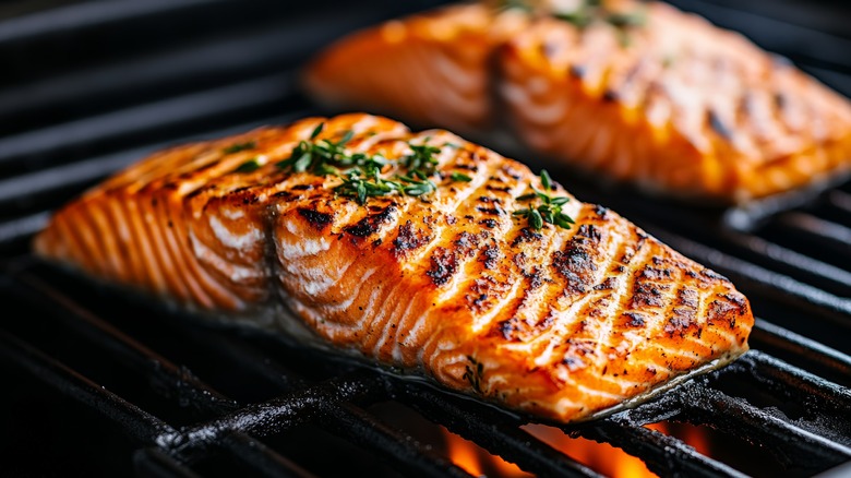 Slices of grilled salmon atop a grill, fire underneath