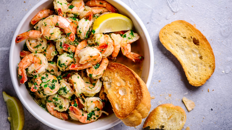 Cooked shrimp in a bowl with slices of lemon and toasted bread