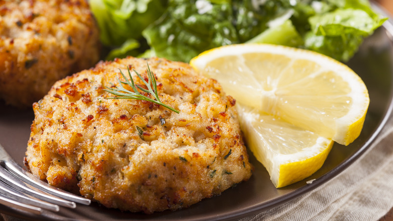 A golden brown crab cake with a slice of lemon