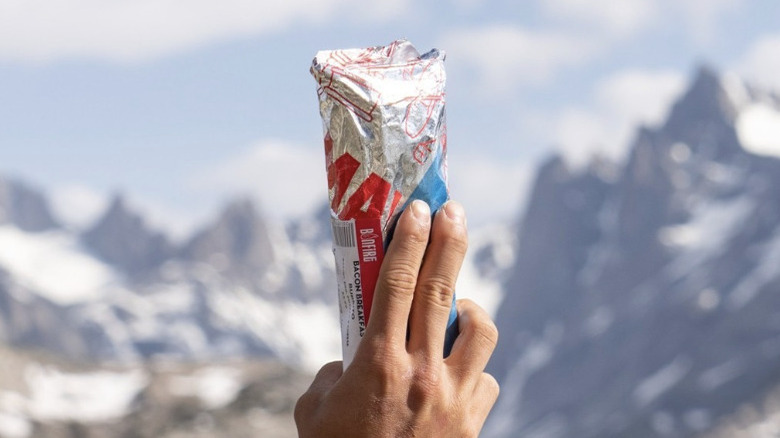 Person holding a Maverik burrito in front of mountains