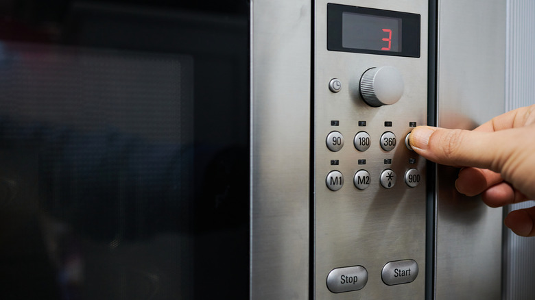 person adjusting settings on a microwave