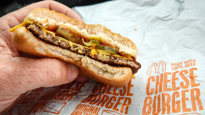 Hand holding half-eaten McDonald's cheeseburger