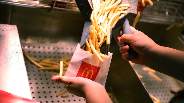 Hands pouring fries into McDonald's packaging