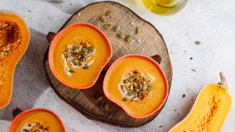 Autumn squash soup in pumpkin bowls on a wooden board