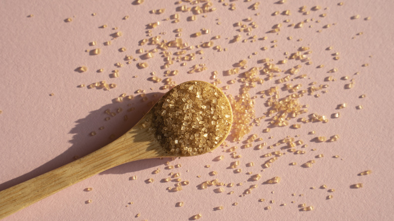 A wooden bowl and a wooden spoon with brown sugar, surrounded by brown sugar cubes.