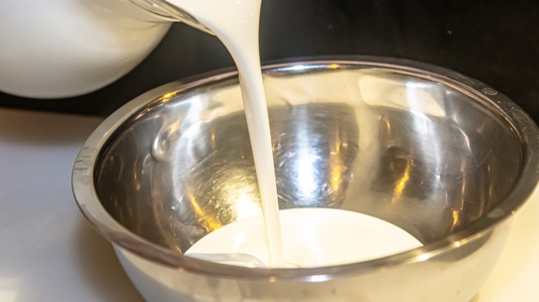 cream being poured into a metal bowl