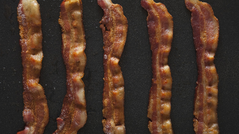 cooked strips of bacon on a black surface