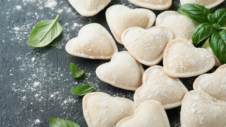 Heart-shaped ravioli with fresh herbs and flour sprinkled on top.