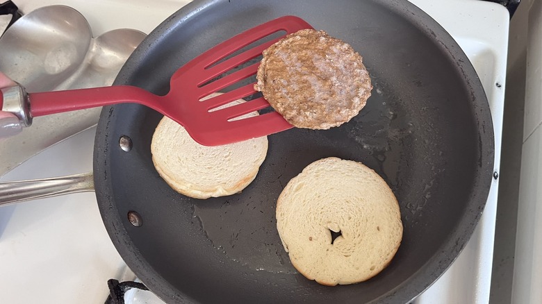 Sausage and bun from a Jimmy Dean sandwich in a frying pan with red spatula