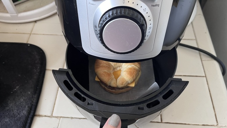 Open drawer of an air fryer showing a Jimmy Dean croissant sandwich inside