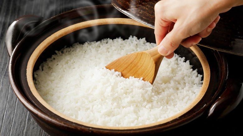 White rice steaming in a hot pot with a wooden spoon