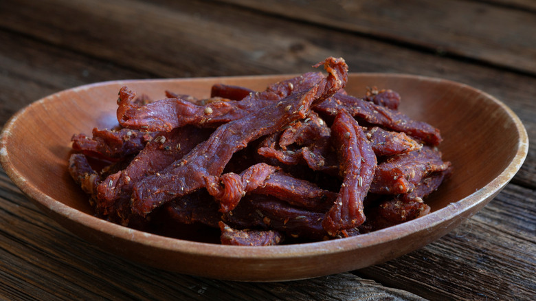 A brown bowl with strips of fresh beef jerky in it