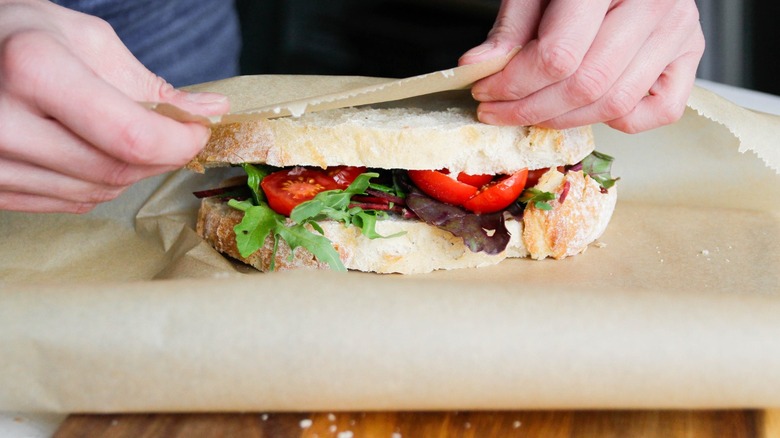 Person wrapping a deli sandwich in parchment paper