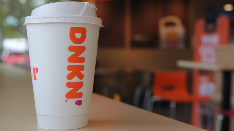 A hot coffee from Dunkin' on a table inside a Dunkin' location