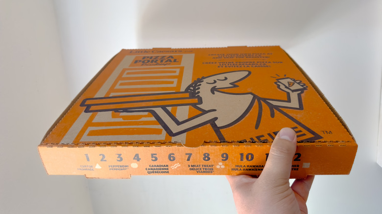 Hand holding Little Caesars pizza box