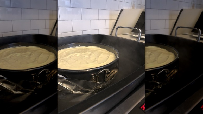 Unbaked cheesecake sitting in a water bath in a pan