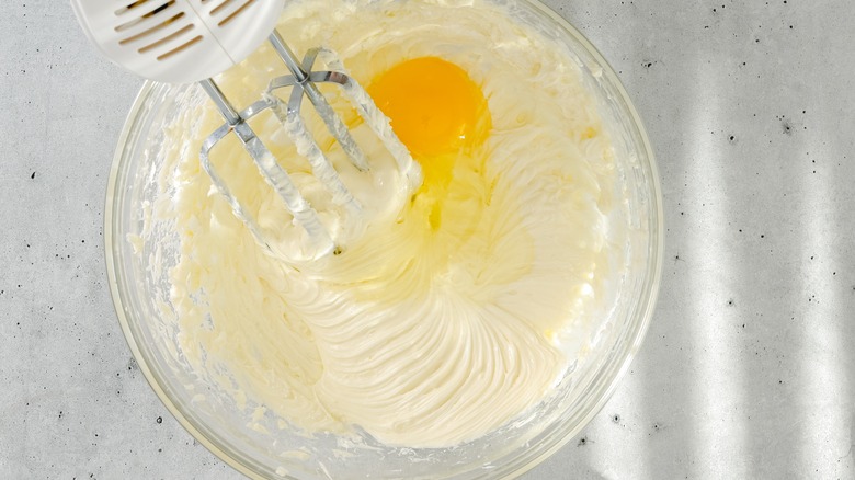 Cheesecake ingredients being whisked in a glass bowl