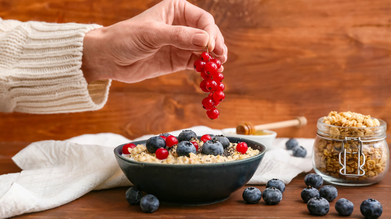 Person adding fresh fruit to cooked oatmeal