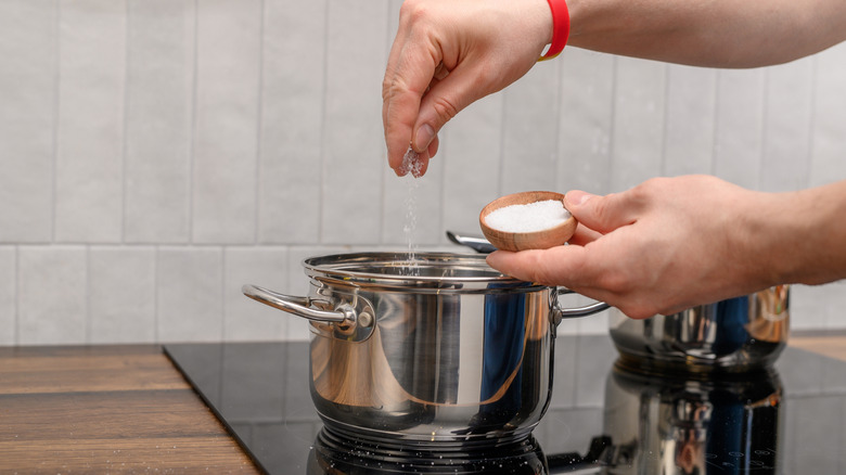 Hand adding salt to pot