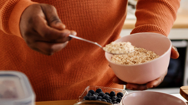 Person preparing oatmeal with blueberries