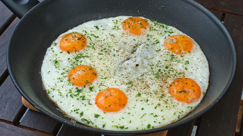 Many fried eggs joined together in a frying pan