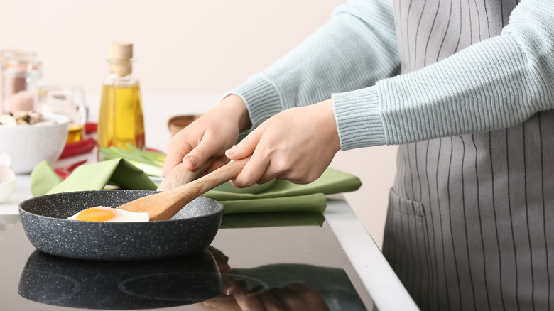 Person flipping eggs with a wooden spatula