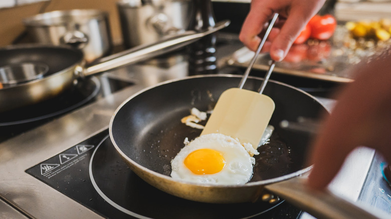 Hand flipping eggs with a spatula