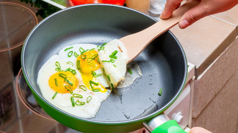 Wooden spatula moving eggs in a frying pan