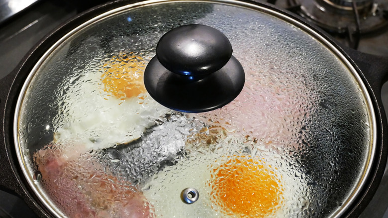 Lid on frying pan with eggs and meat inside