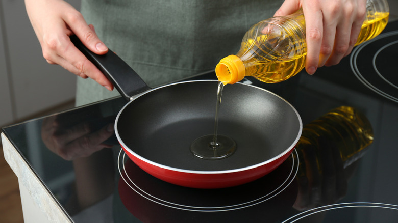 Person pouring oil into a frying pan