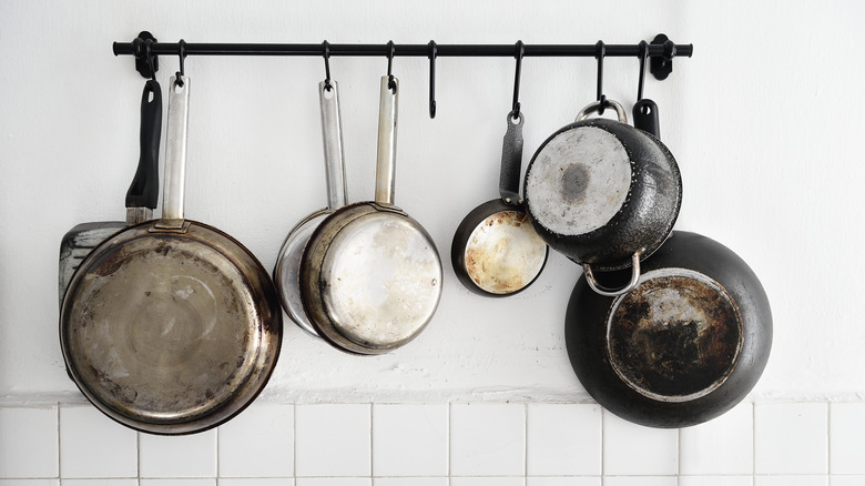 Frying pans and pots hanging from kitchen wall