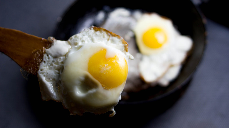 Fried eggs picked up by thick wooden spatula