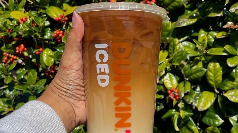 A photo of a hand holding a "blueberry cobbler iced macchiato"