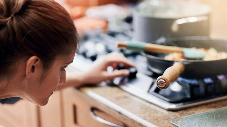 Woman adjusting stove temperature