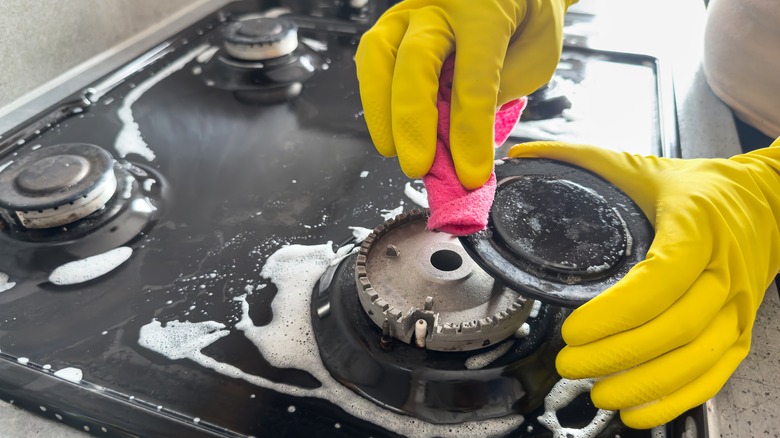 Person cleaning a gas stove