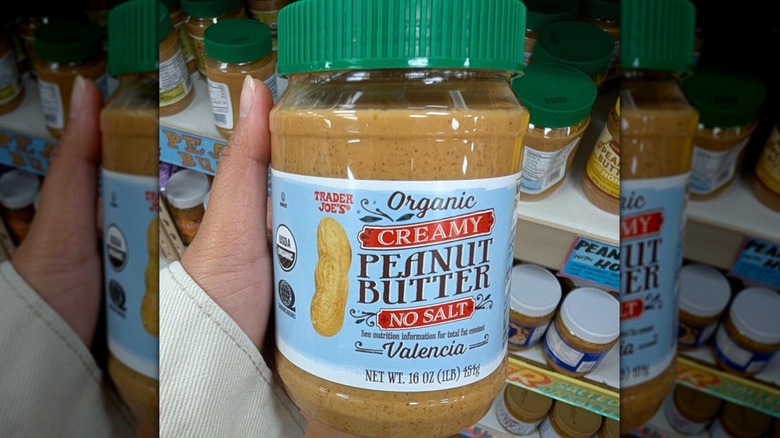 Hand holding tub of peanut butter at Trader Joe's