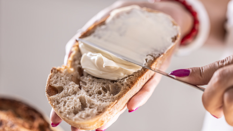 A person spreading butter on bread with a knife