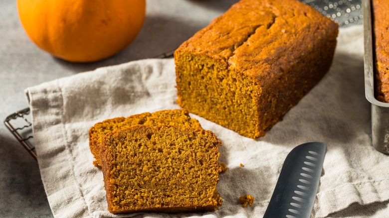 sliced loaf of homemade pumpkin bread on a beige cloth napkin