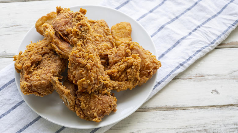 A plate of super crunchy fried chicken sits on a wooden table.