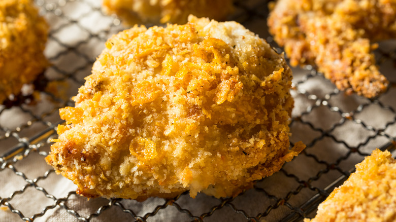 A piece of fried chicken sits on a wire rack.