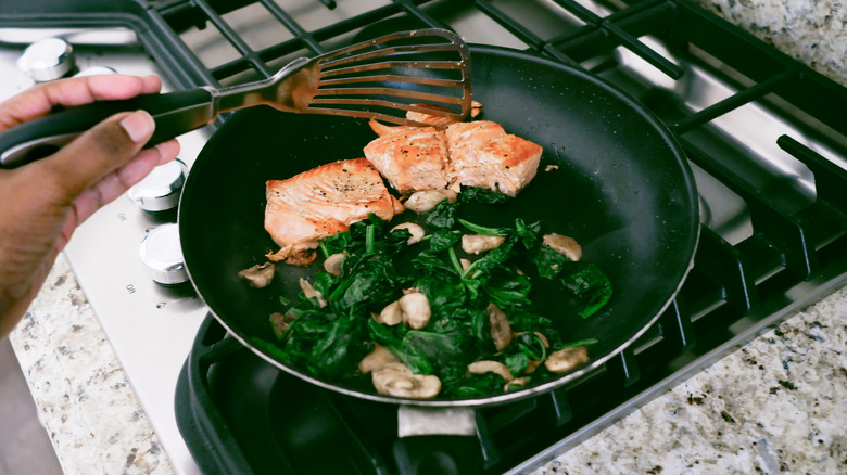 Pan frying fish with spinach and mushrooms