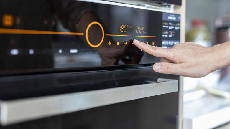 A hand adjusts temperature on an oven