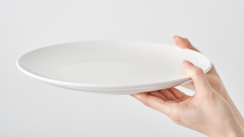 woman's hands holding a white plate