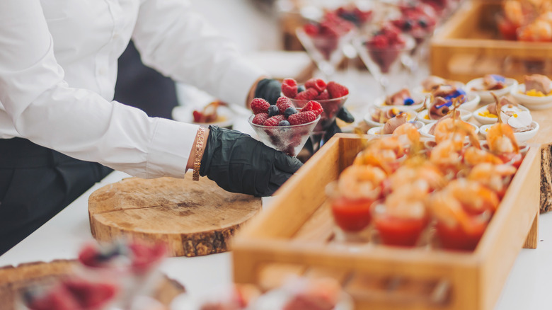 A server wearing gloves to put out food at a buffet