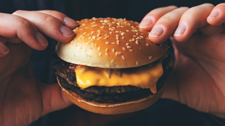 A person holding a burger.