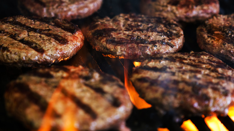 Burgers patties cooking on a grill.