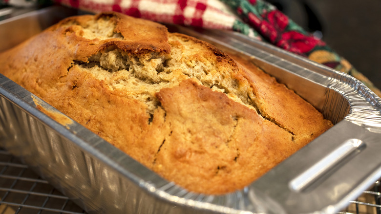 Cracked banana bread in an aluminum tin.